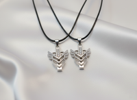 Two silver pendants on black cords against a light gray background
